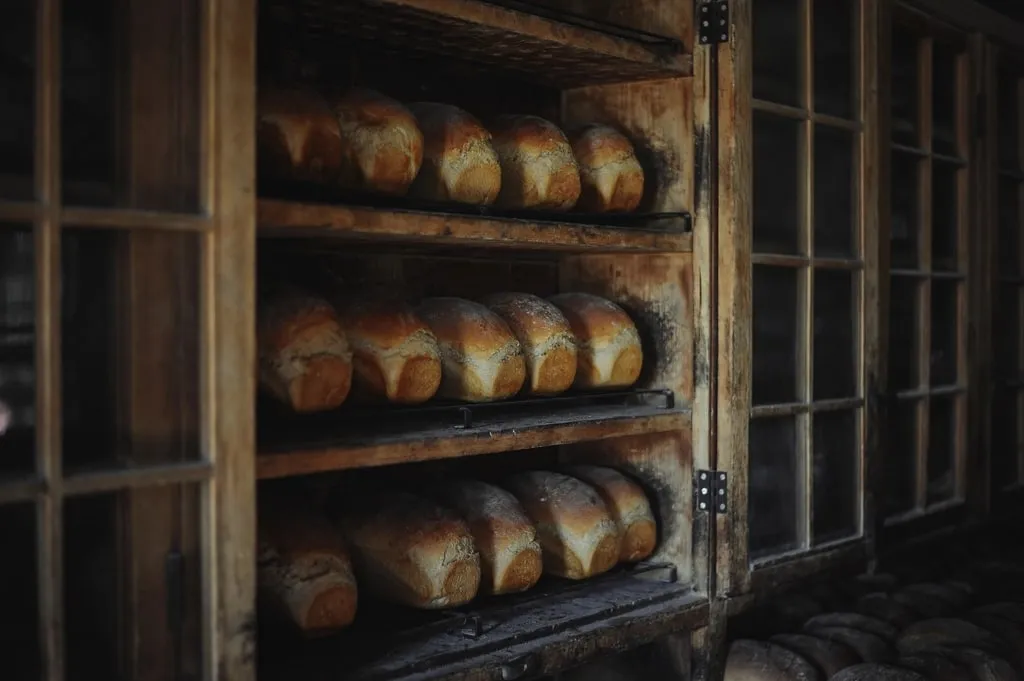 Pains de mie alignés sur les étagères en bois du fournil